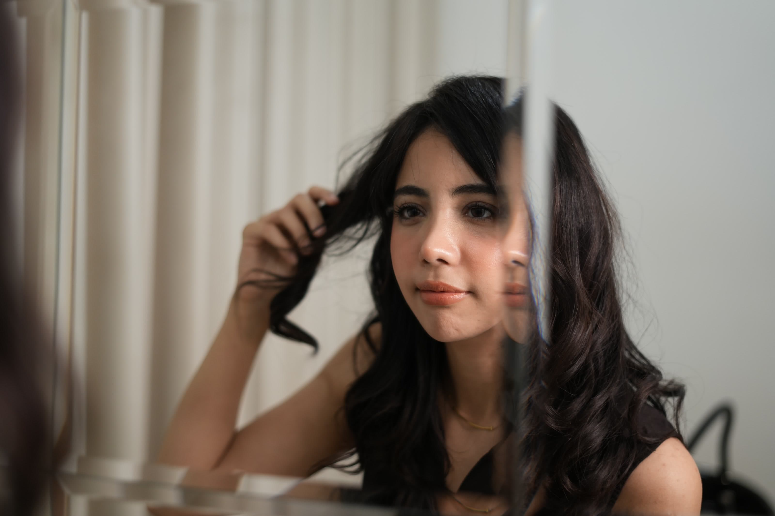 Client studying the texture of her finished hair in the mirror.